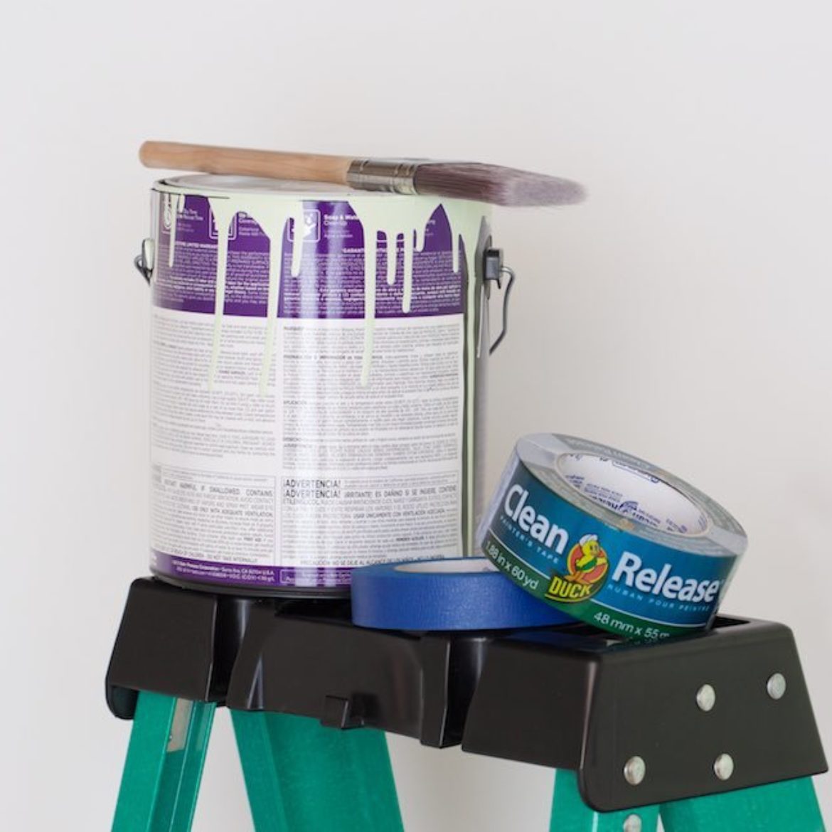 A bucket of paint sitting on a ladder.