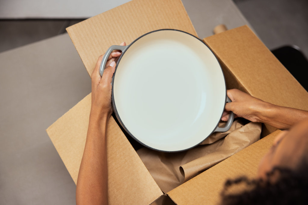 A pan being placed in Flourish Kraft Paper within a box