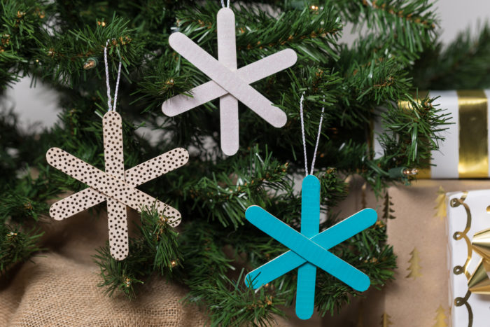 Popsicle snowflake ornaments hanging in a tree.