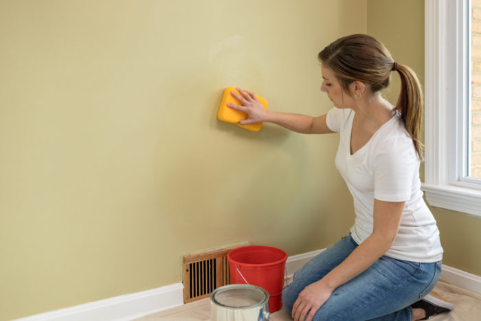 Person washing wall with sponge.