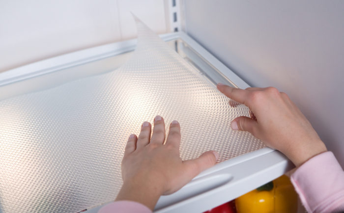 Clear Classic liner being placed over a shelf in the refrigerator