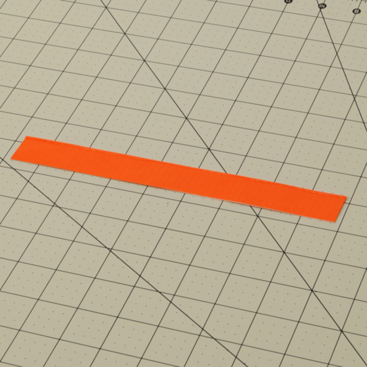 Strip of Orange Duck Tape filded length wise to create a double sided strip of Duck Tape