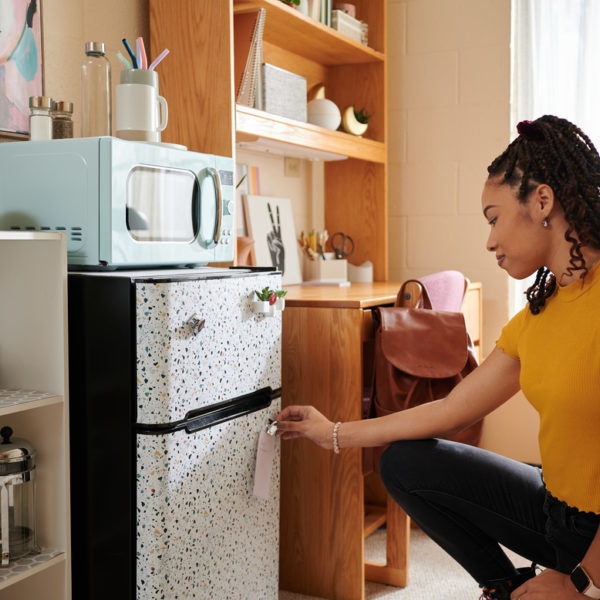 Woman placing EasyLiner shelf liner on dorm mini fridge