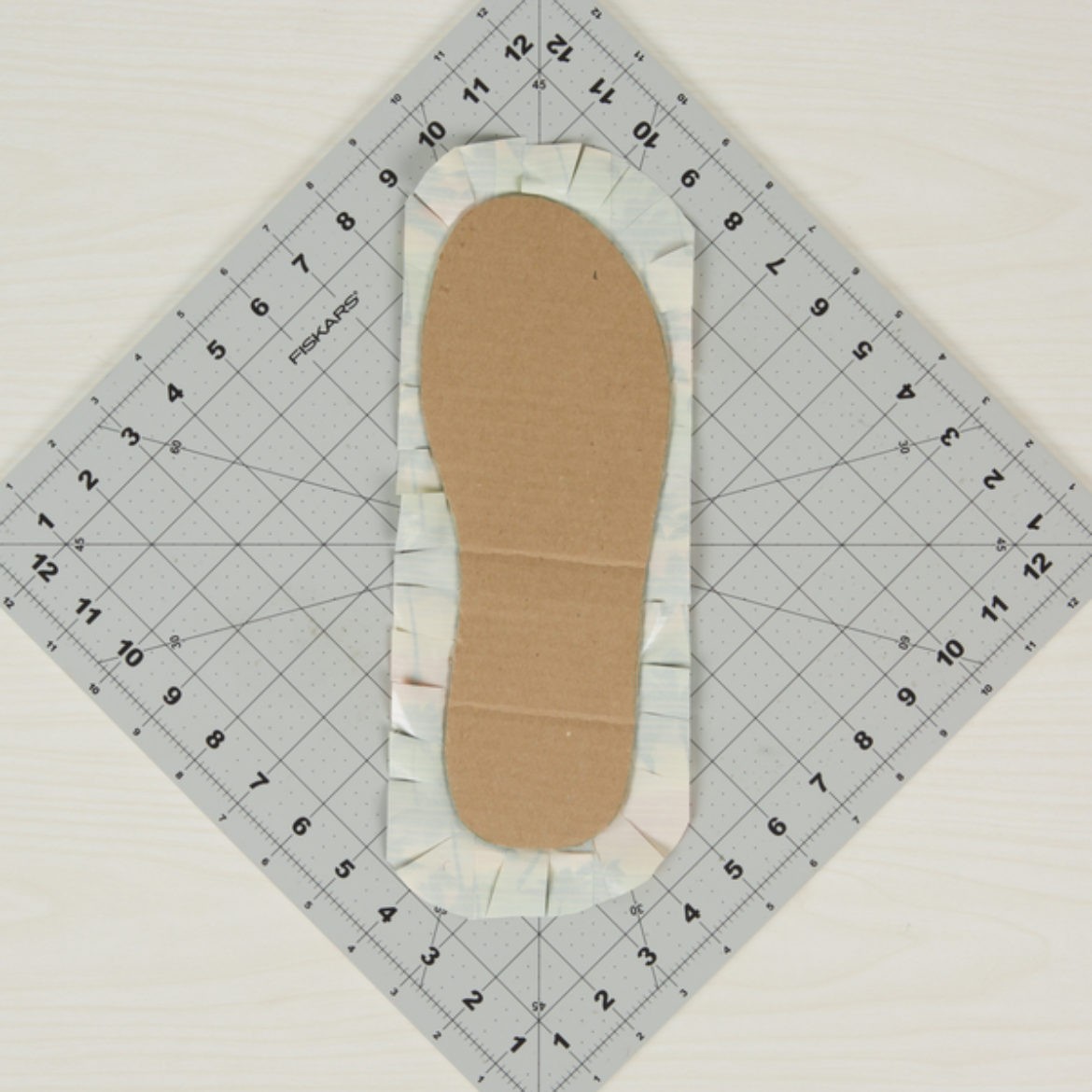 flip over the piece from the previoius step and trim so that there is a boarder of sticky side going around the outside of the flip flop shape. Small slits made into the sticky side
