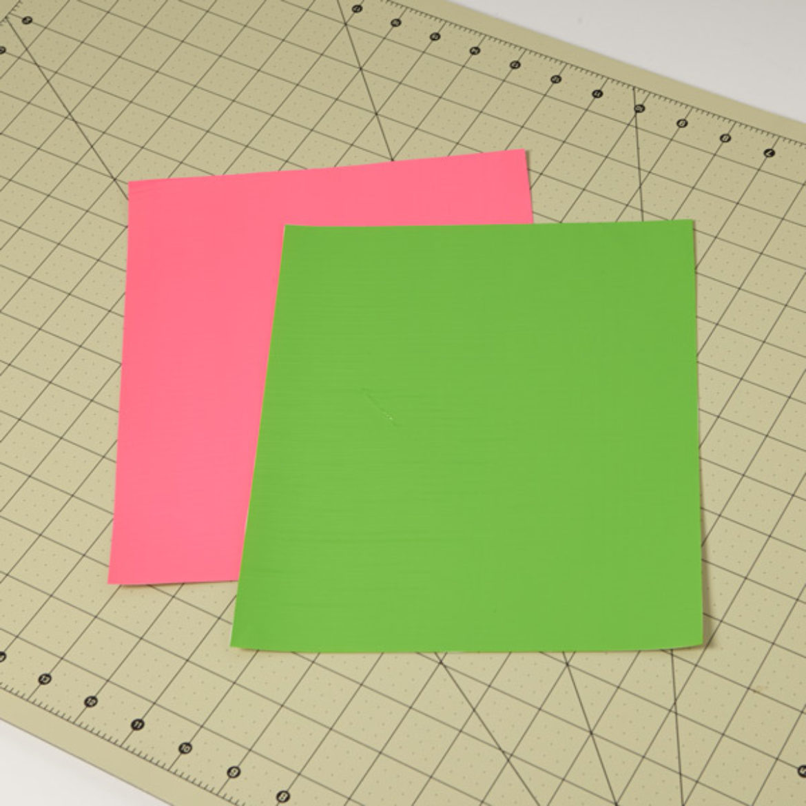 one pink and one green Duck Tape fabric sheet placed on a crafting board