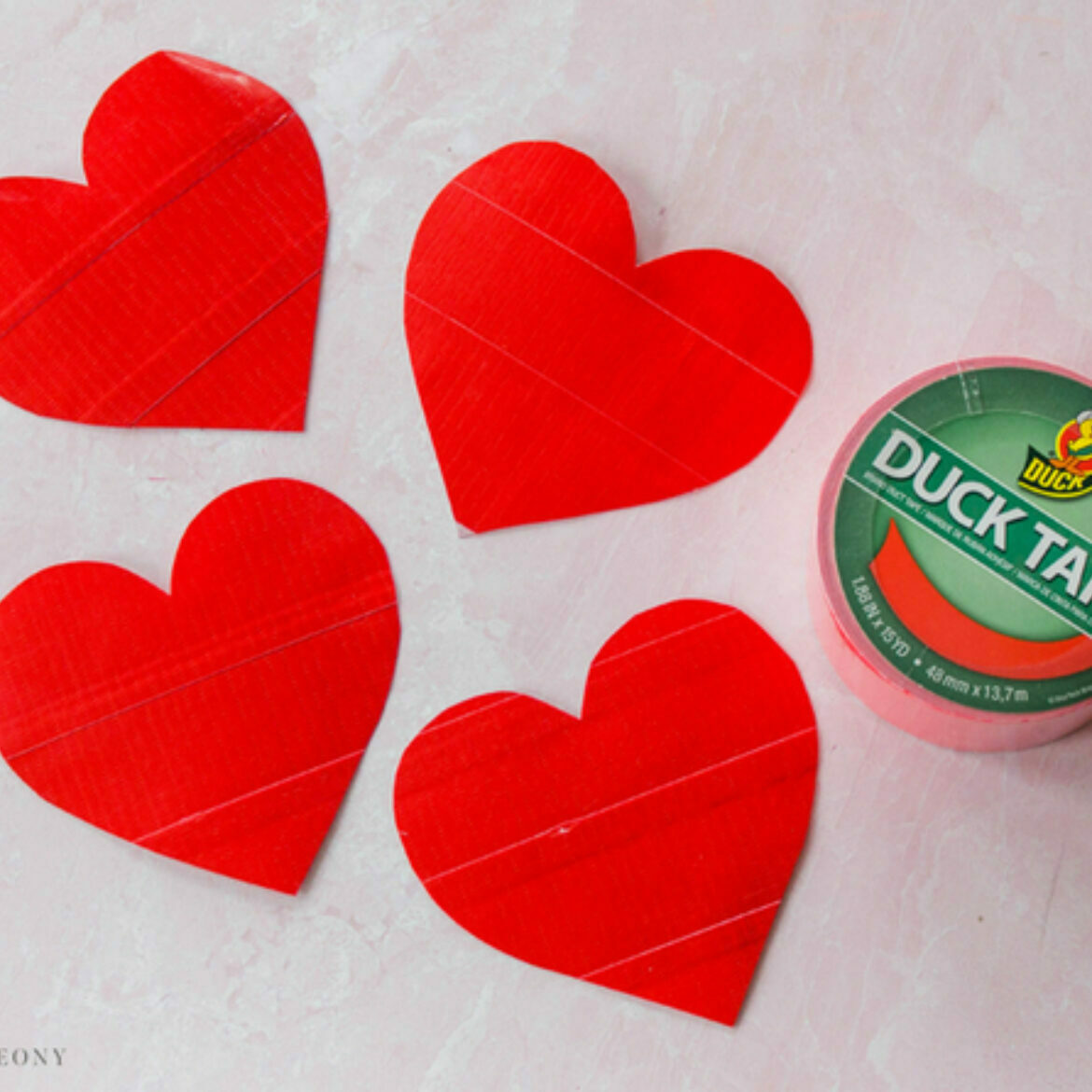 Four duct tape hearts with a roll of red duct tape