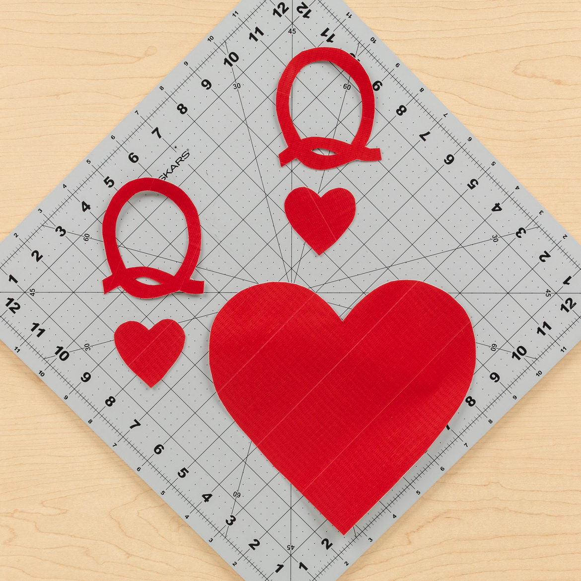 2 Qs, 2 small hearts and one large heart cut out of a red Duck Tape fabric sheet