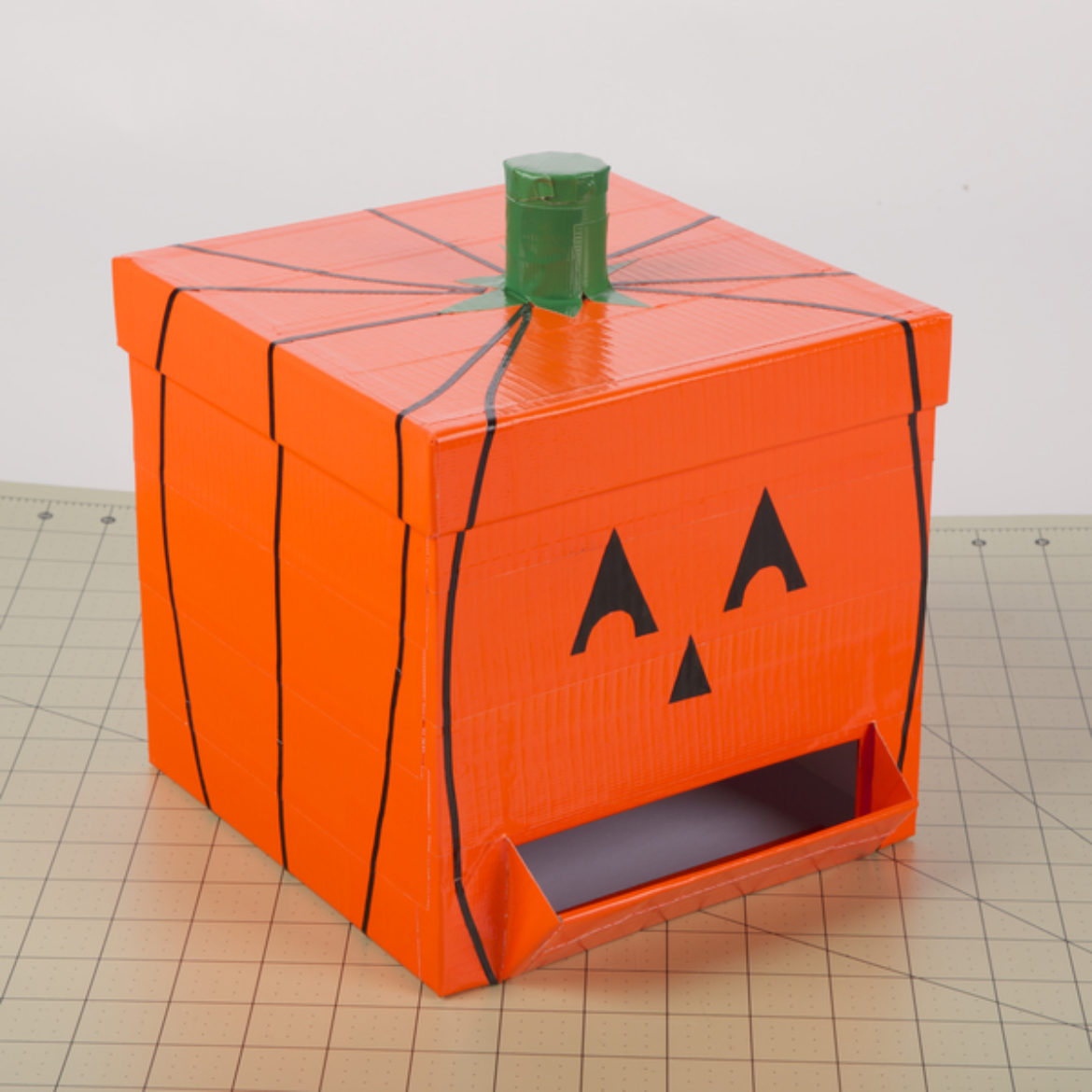 Step attached to the top of the box, strips from step 8 attached vertically around the pumpkin, and the face cut outs added to the front