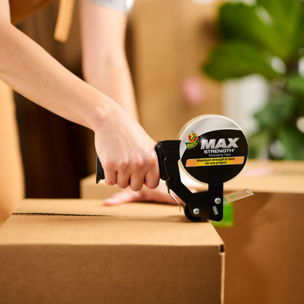 A person taping a box shut with Duck Max Strength Packing Tape.